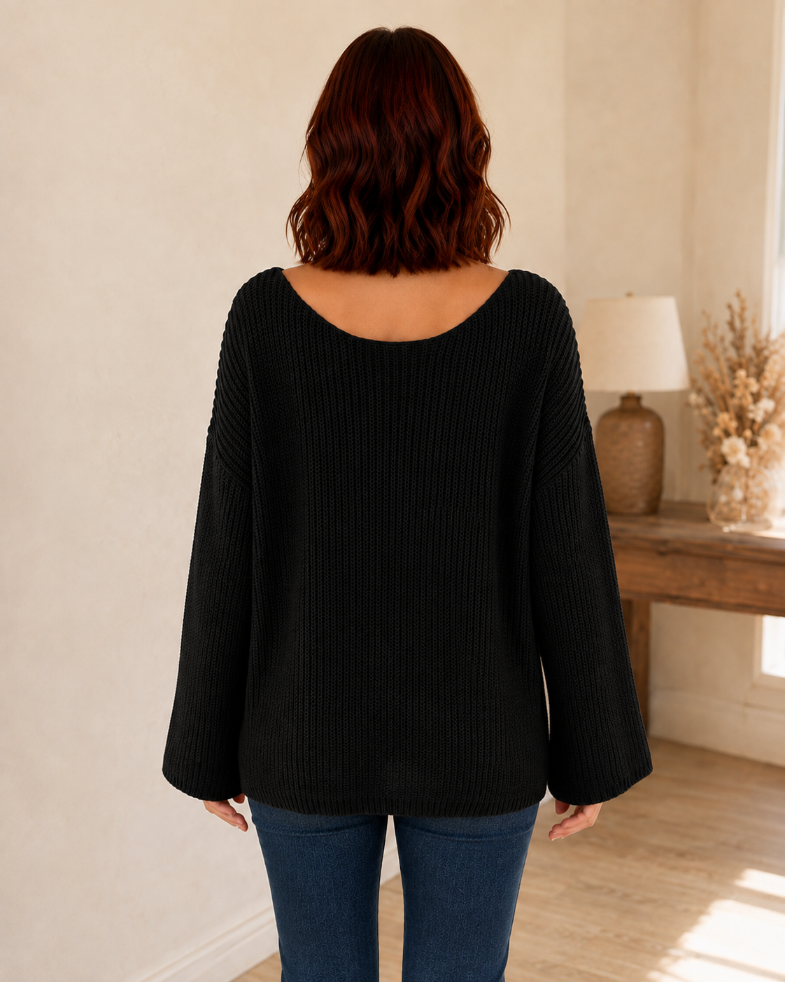 Straight back view of a black open-knit sweater with a wide scoop neckline and bell sleeves