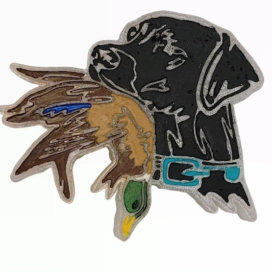 Black Labrador car freshie holding a duck, with a turquoise collar, silver-colored outline, and green and brown duck details.