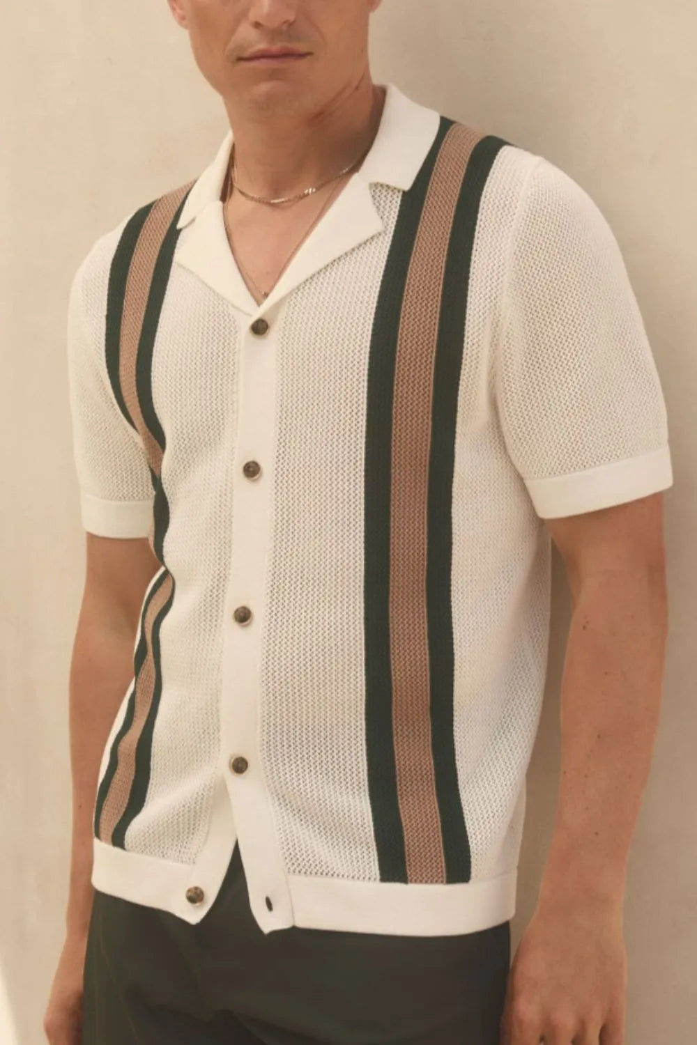 Man wearing an ivory short sleeve button-down shirt with contrast vertical stripes and textured knit fabric