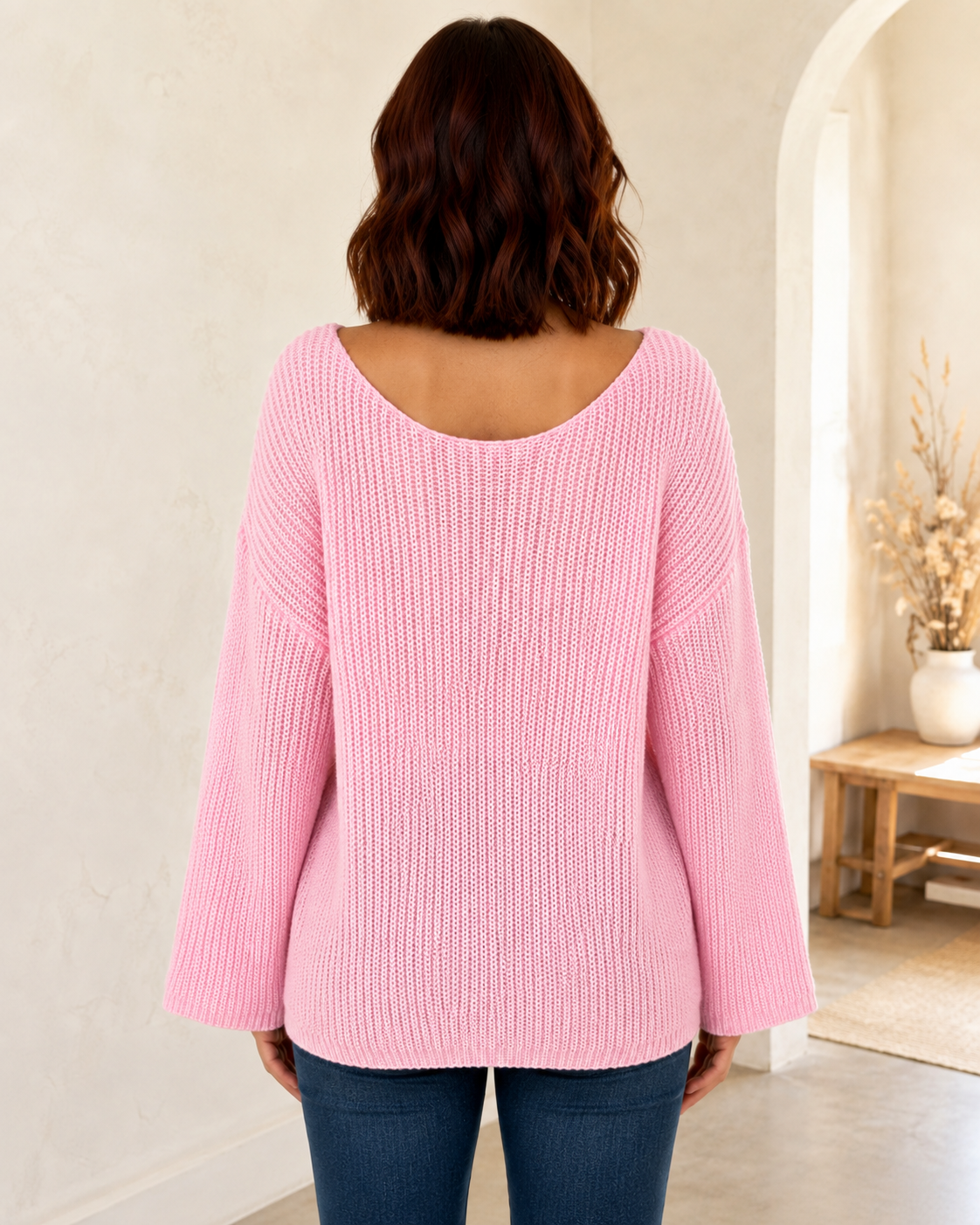 Straight back view of a pink open-knit sweater with a wide scoop neckline and bell sleeves