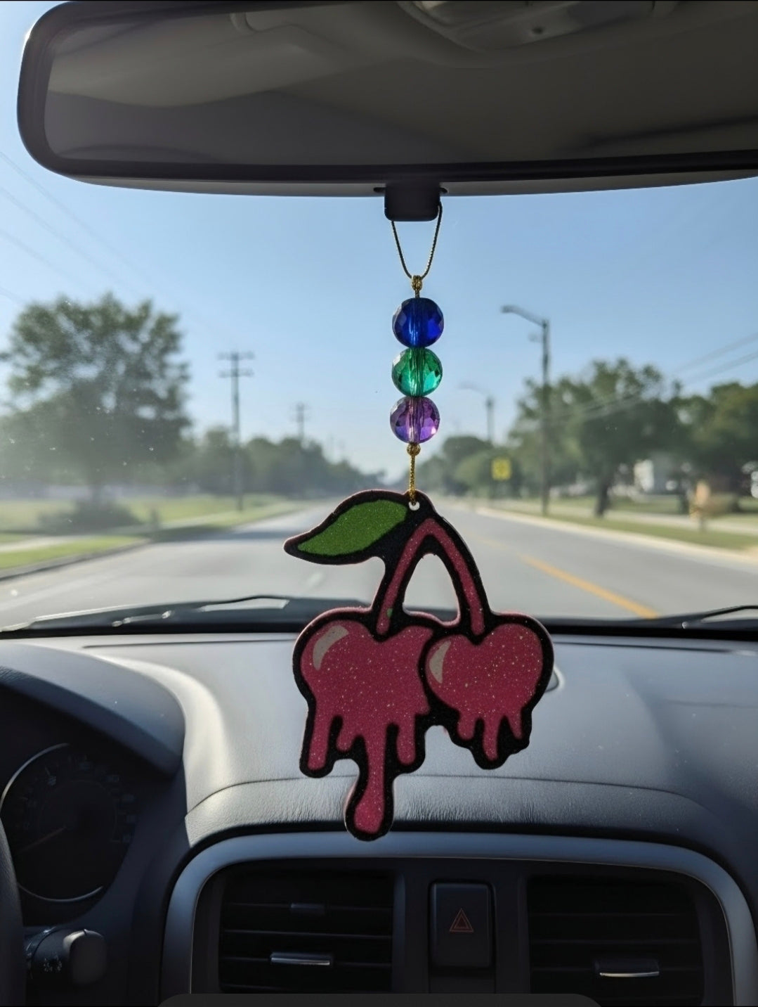 Handmade pink dripping cherry freshie shown hanging from a rearview mirror with colorful accent beads.