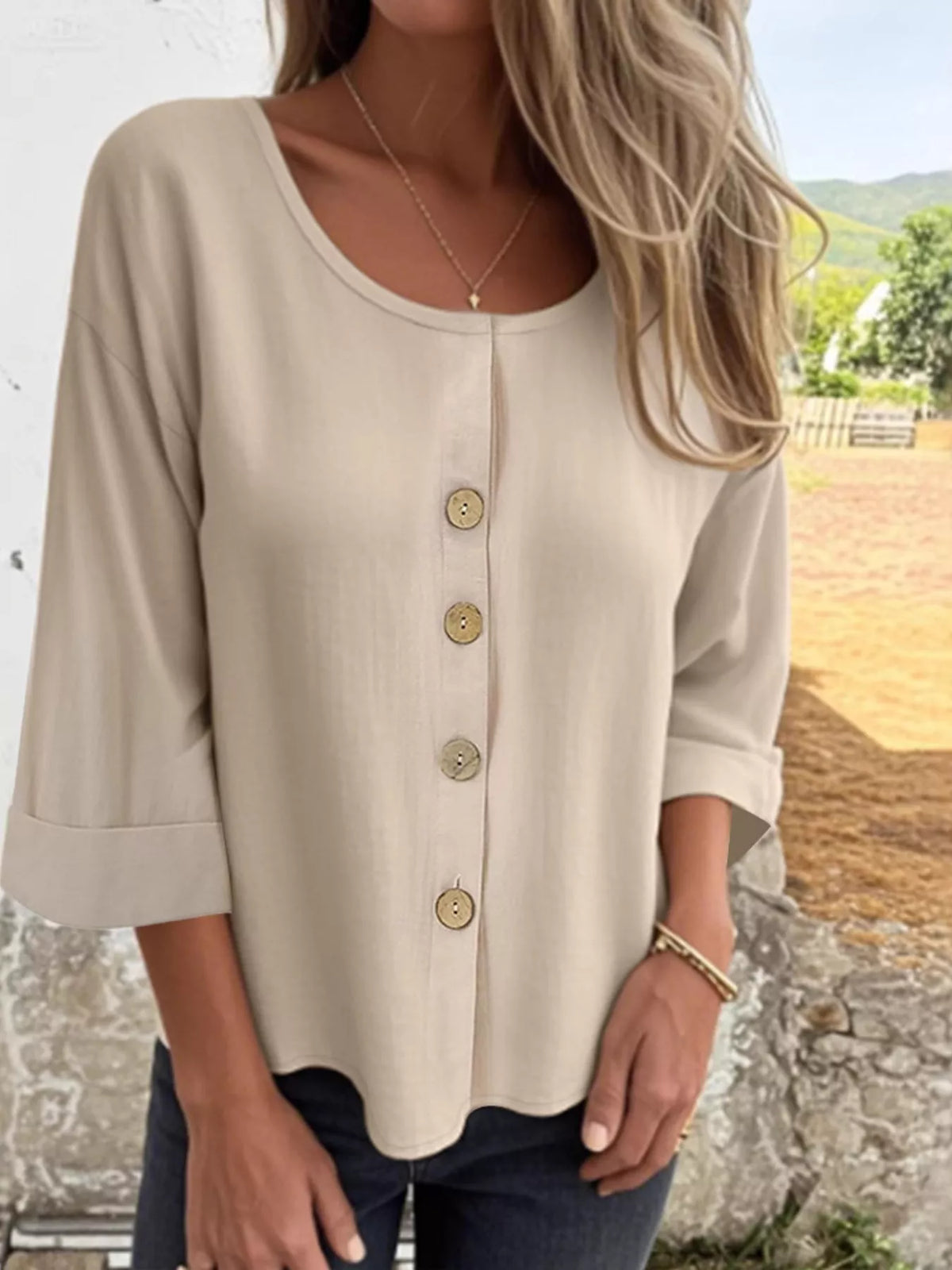 Woman wearing a beige V-neck button-front 3/4 sleeve blouse