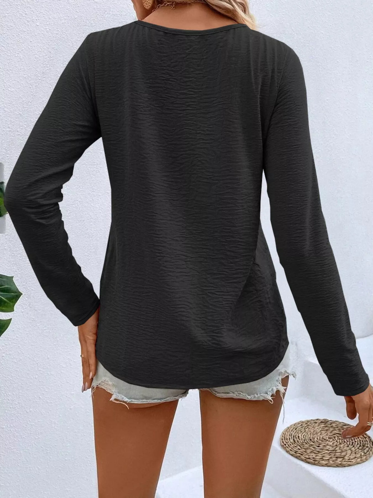 Back view of women's black long sleeve V-neck top