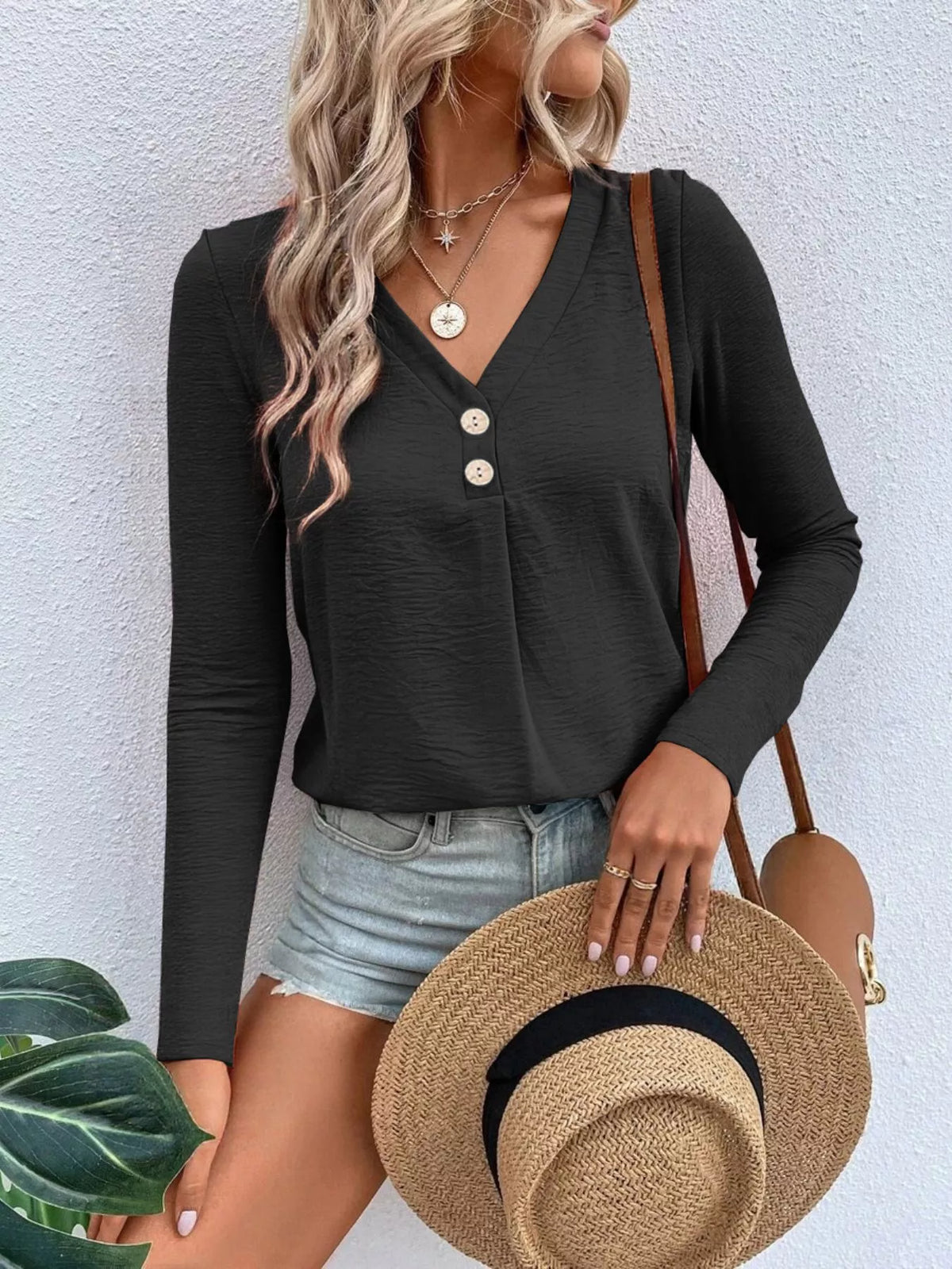 Woman wearing a black V-neck button detail long sleeve top