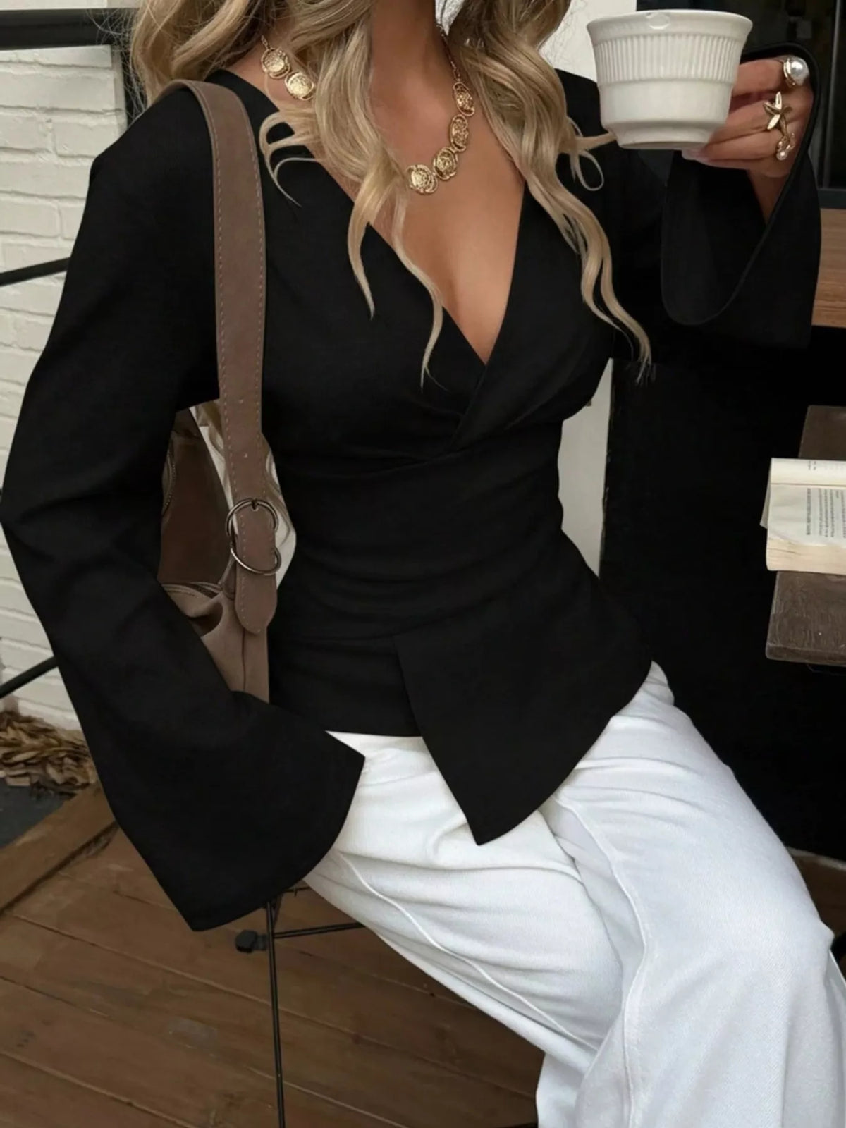 Side view of women's black wrap blouse with flared long sleeves