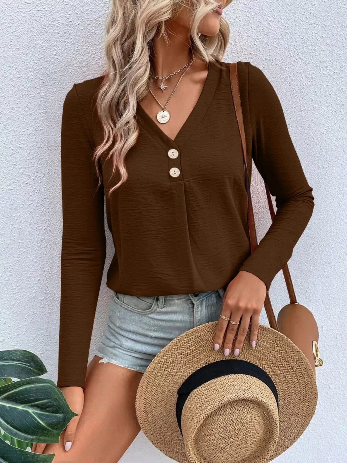 Woman wearing a dark brown V-neck button detail long sleeve top