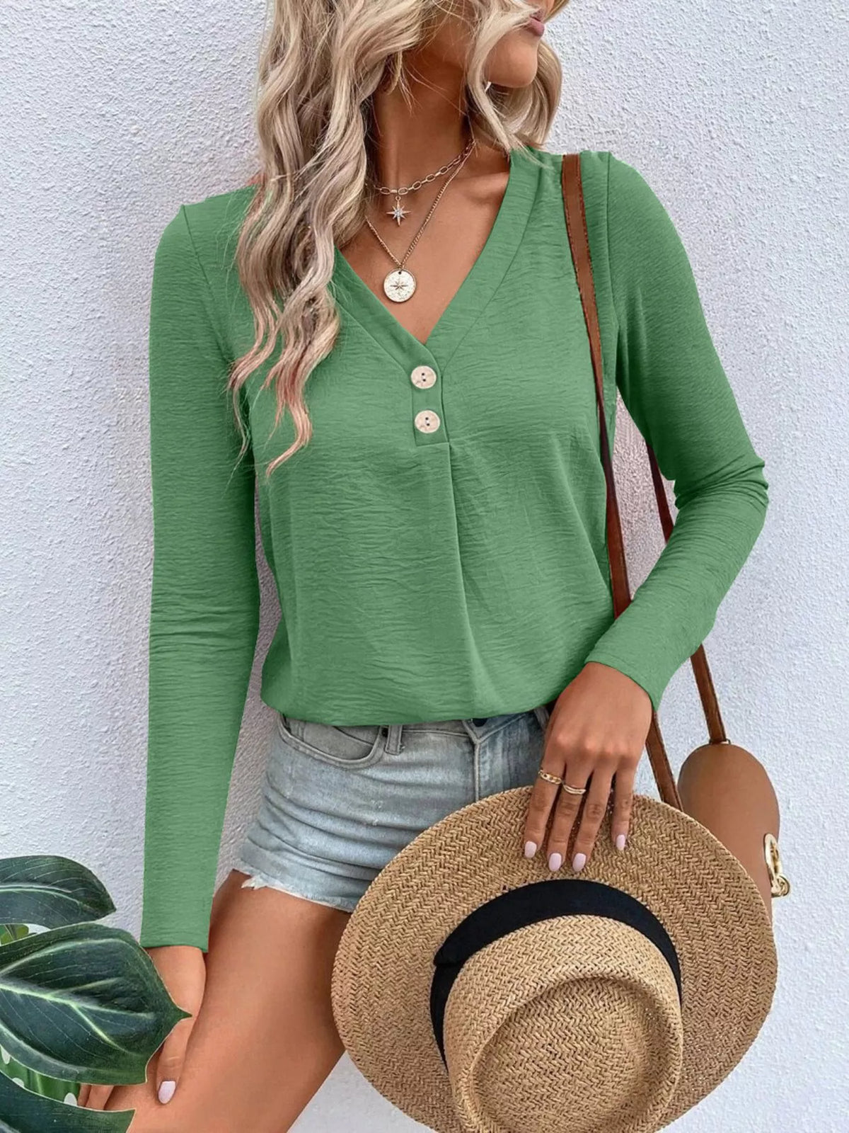 Woman wearing a grass green V-neck button detail long sleeve top