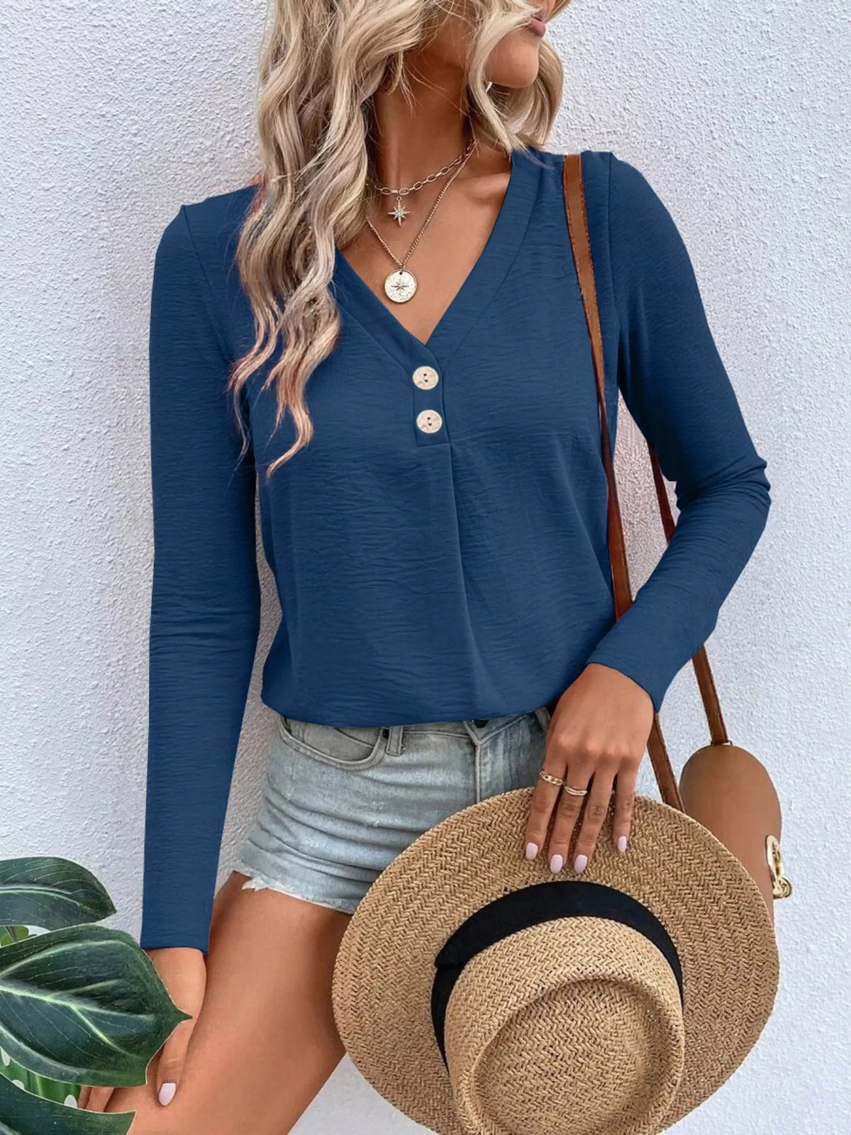Woman wearing a navy blue V-neck button detail long sleeve top