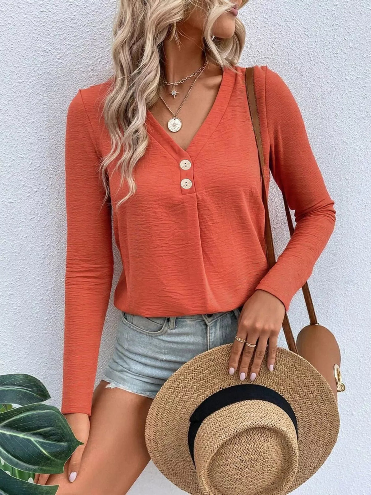 Woman wearing an orange V-neck button detail long sleeve top