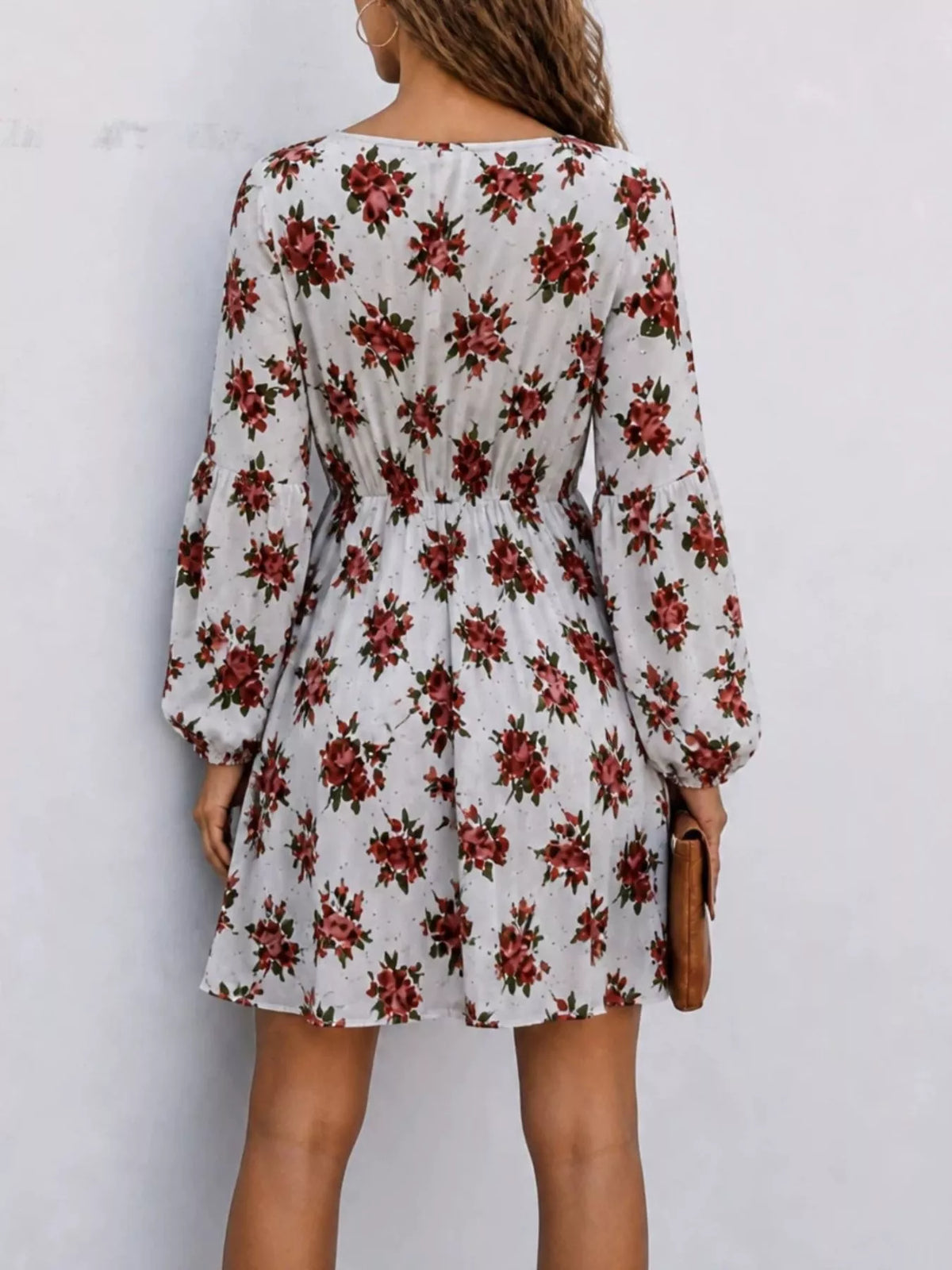 Woman wearing a white floral print V-neck long sleeve mini dress, back view