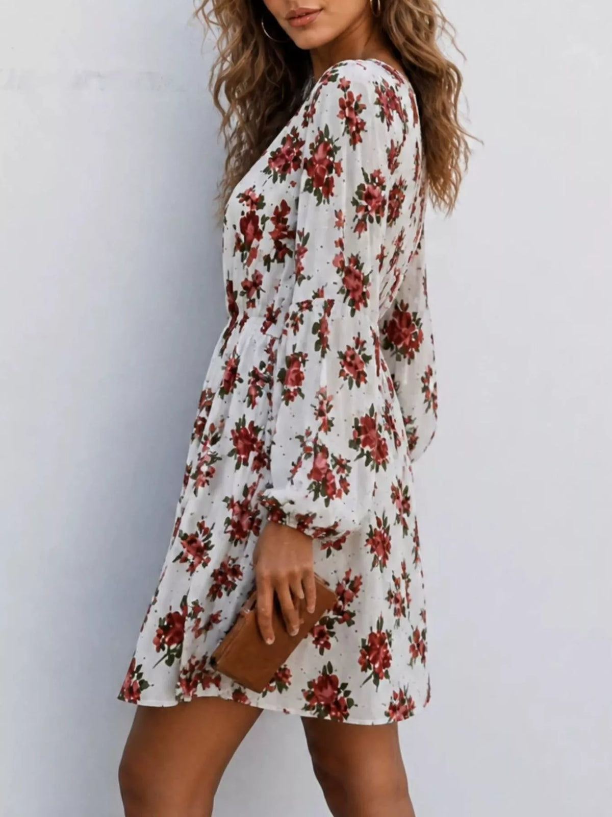 Woman wearing a white floral print V-neck long sleeve mini dress, side view